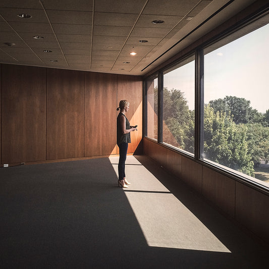 woman standing in empty office room at window