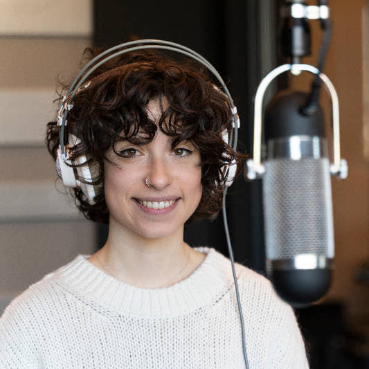 A young curly hair singer woman recording vocal in booth