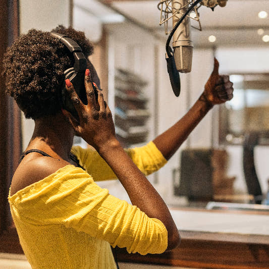 Female singer thumb up while recording vocal in booth