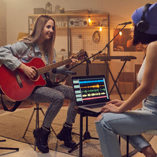Female guitarist recording guitar in band practice room