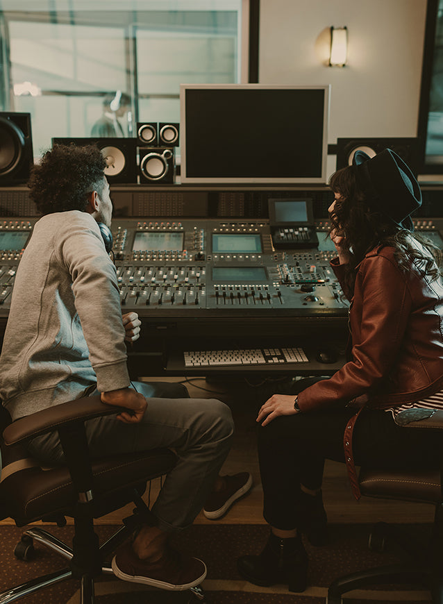 Two men talk front of recording colsole in recording studio mobile