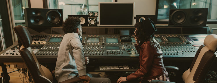 Two men talk front of recording colsole in recording studio